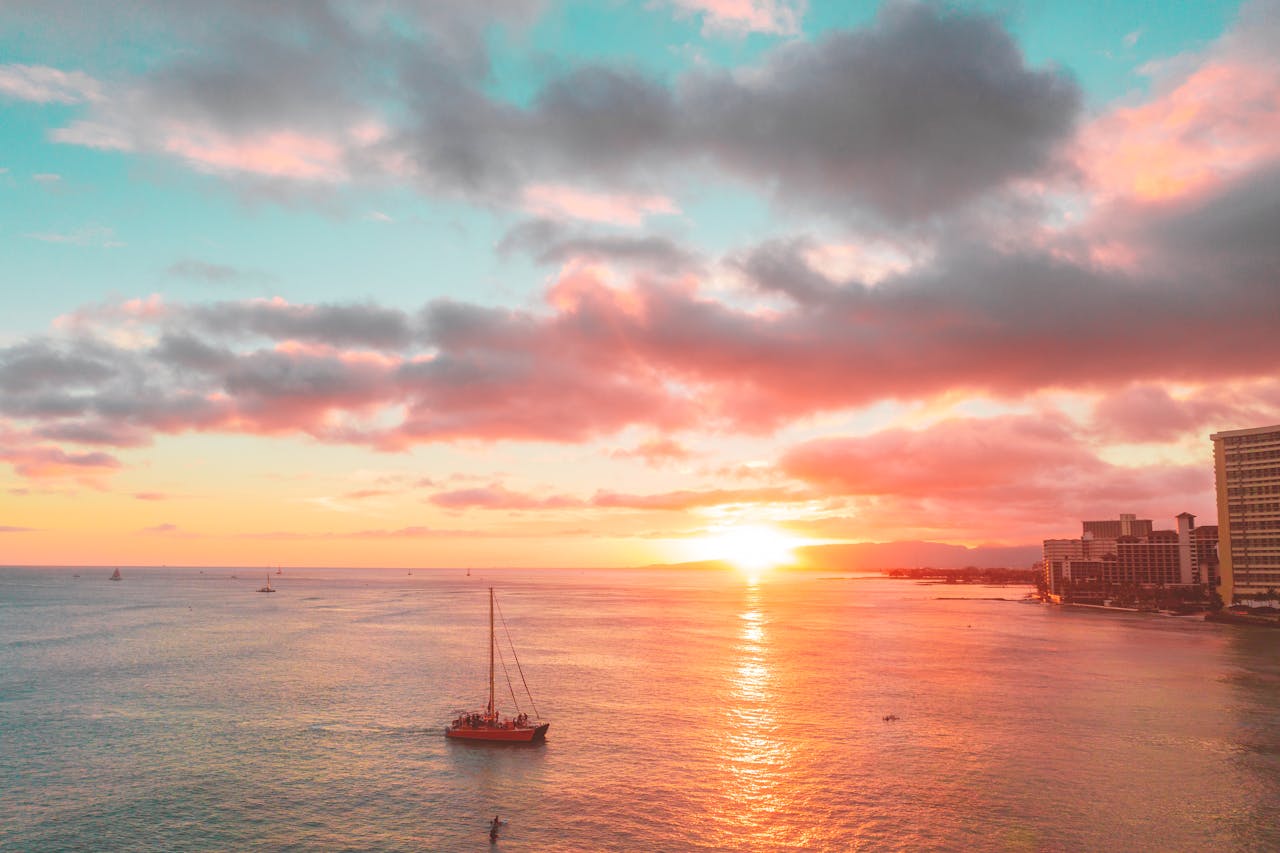 Stunning sunset over the ocean with sailboats and city skyline, capturing vibrant colors and tranquility.